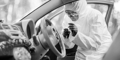 crime scene investigator collecting prints from car steering wheel