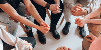 support group in meeting - close up on their hands in a circle