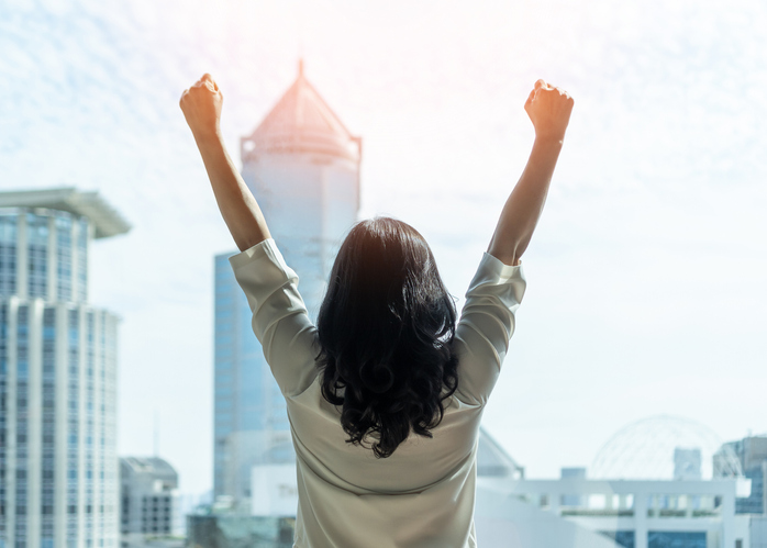 Woman leader raising her arms to the city scape